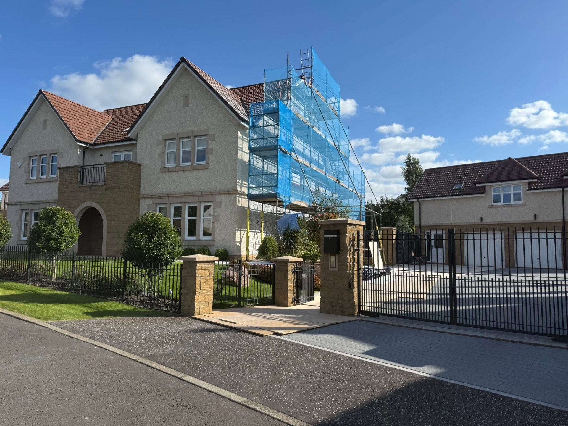 Scaffold set up on a rendered detached home behind gated driveway