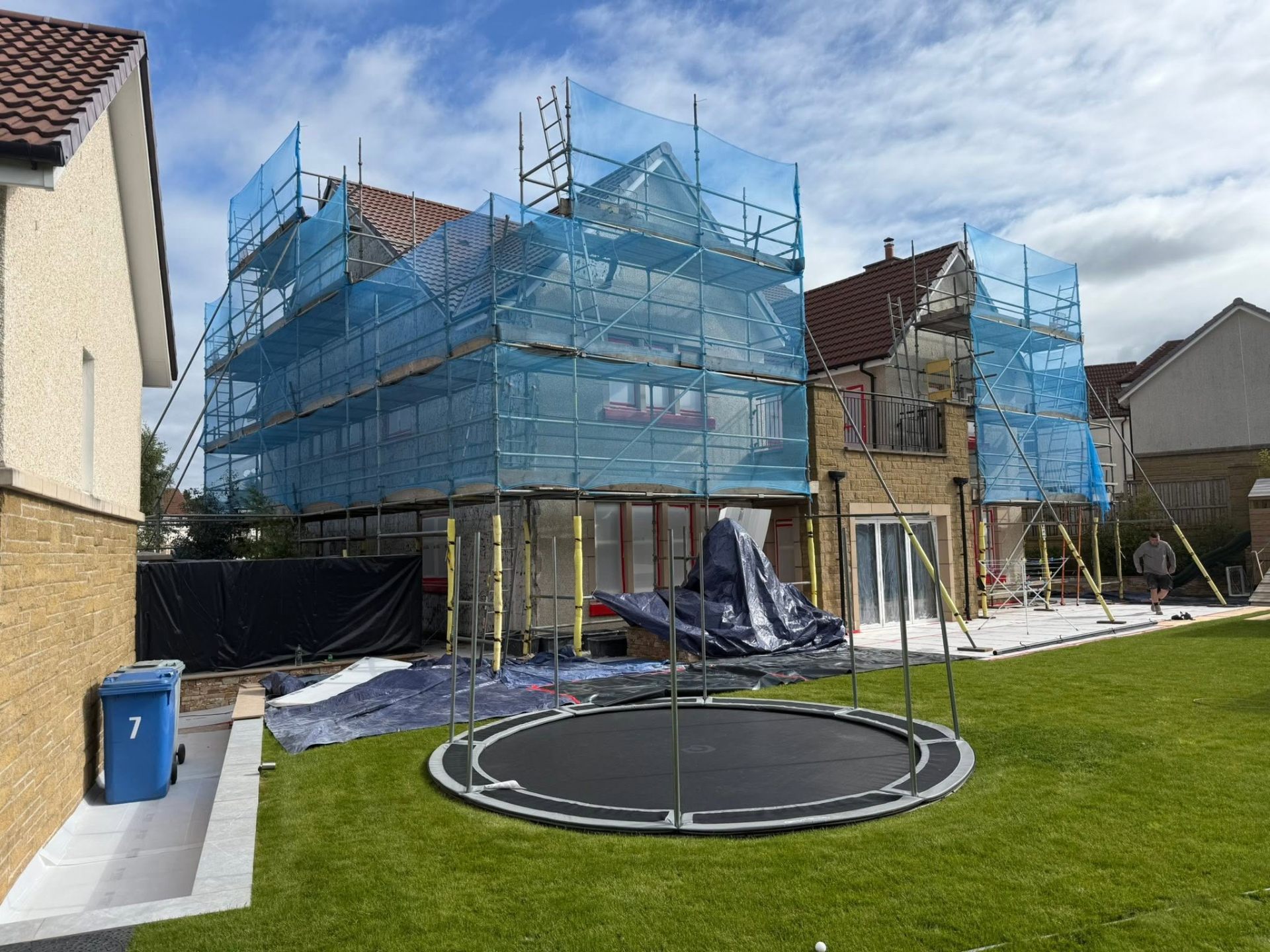 Full scaffold and safety netting around a large detached home under render